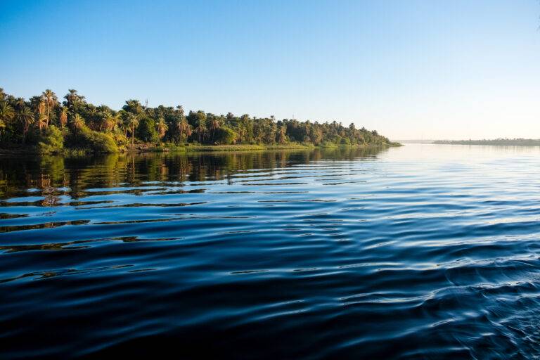 The majestic Nile River flowing peacefully through Aswan, Egypt, under a clear blue sky