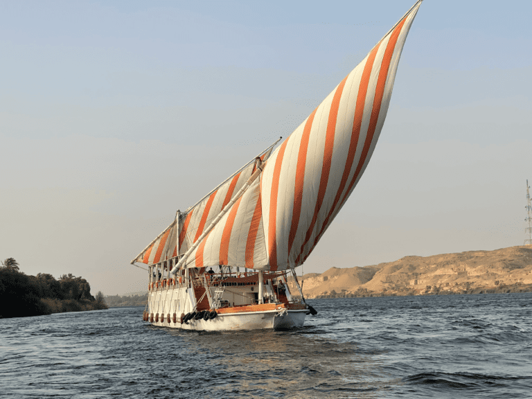 a dahabiya in the middle of the Nile in Aswan with a large sail