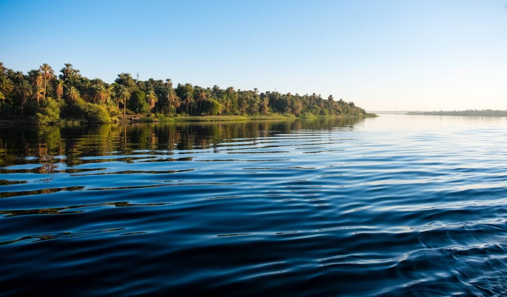 The majestic Nile River flowing peacefully through Aswan, Egypt, under a clear blue sky