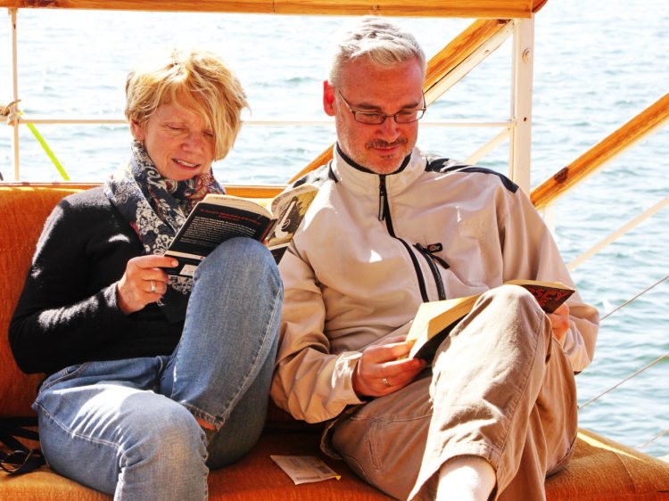 two guests in the dahabiya are reading books together smiling